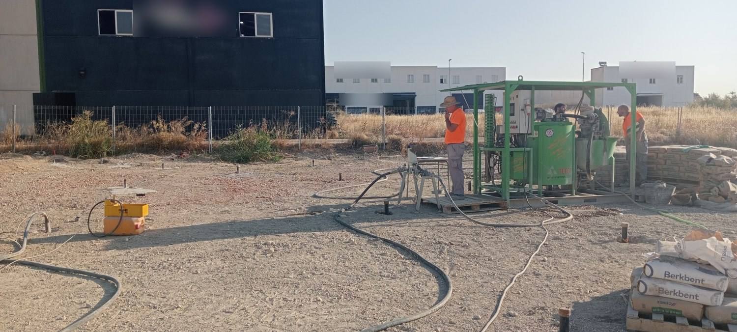 Vista general del solar durante la inyección: bocas de tubos asomando del terreno, mangueras tendidas hacia la central de inyección y sacos de cemento.
