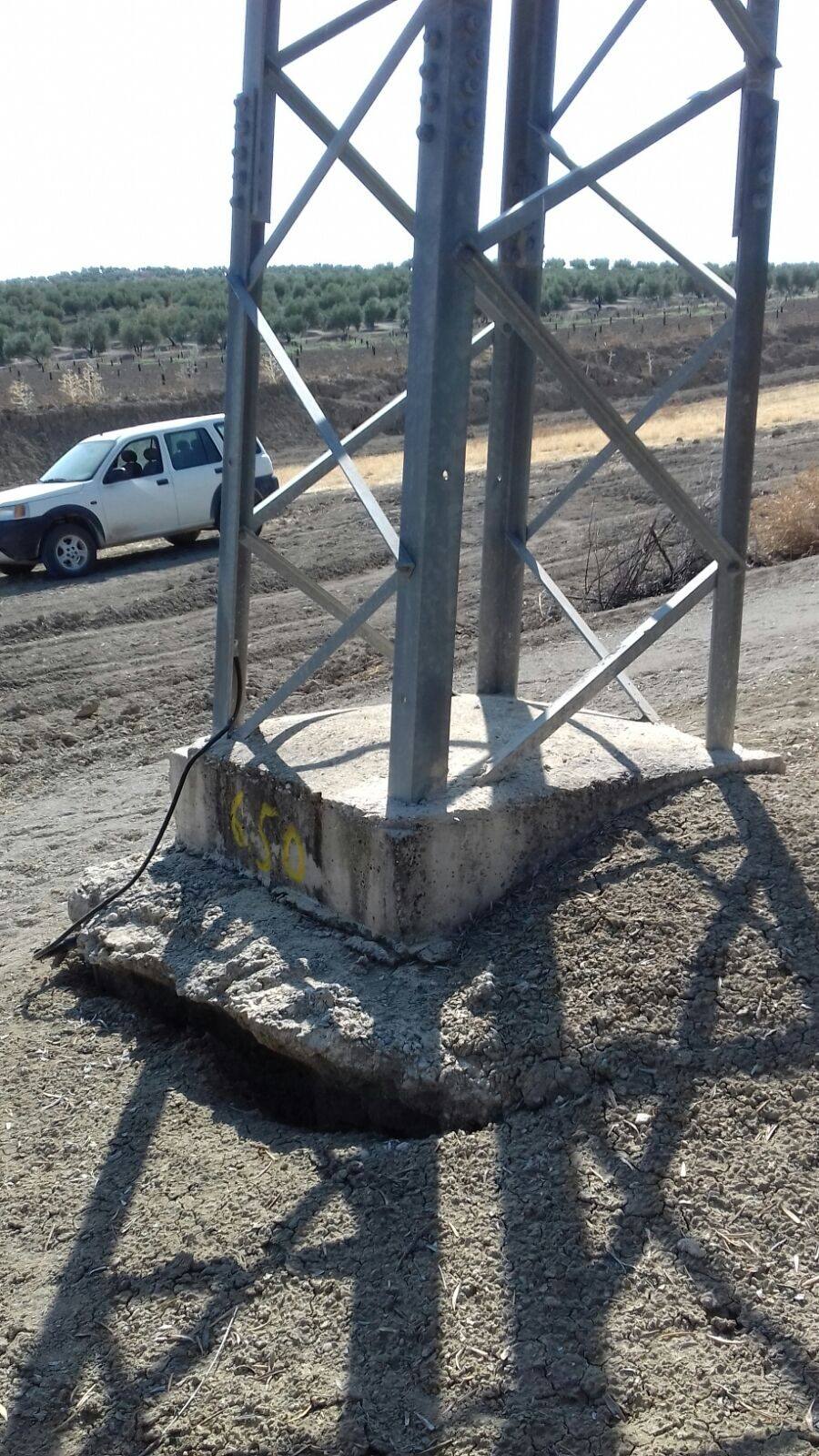 Pata de un apoyo de celosía sobre su peana de hormigón, con la losa de la base rota y levantada alrededor.