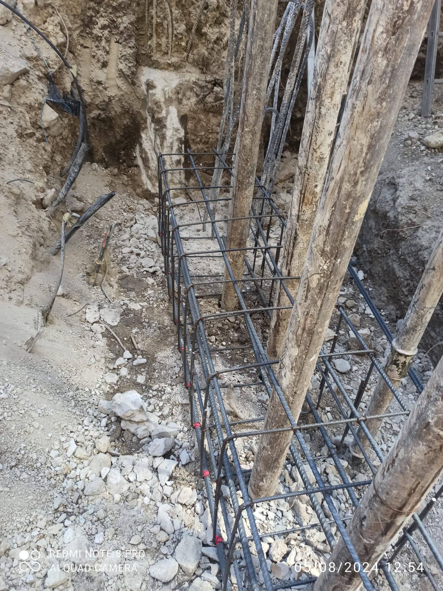 Pantalla de micropilotes descubierta en la excavación, con la armadura de la viga de atado montada a su pie.